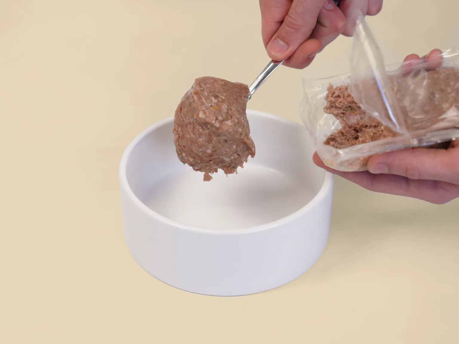A hand spoons a patty of Big Dog Pet Foods Turkey Low Allergy, Single Protein Raw Diet into a bowl.