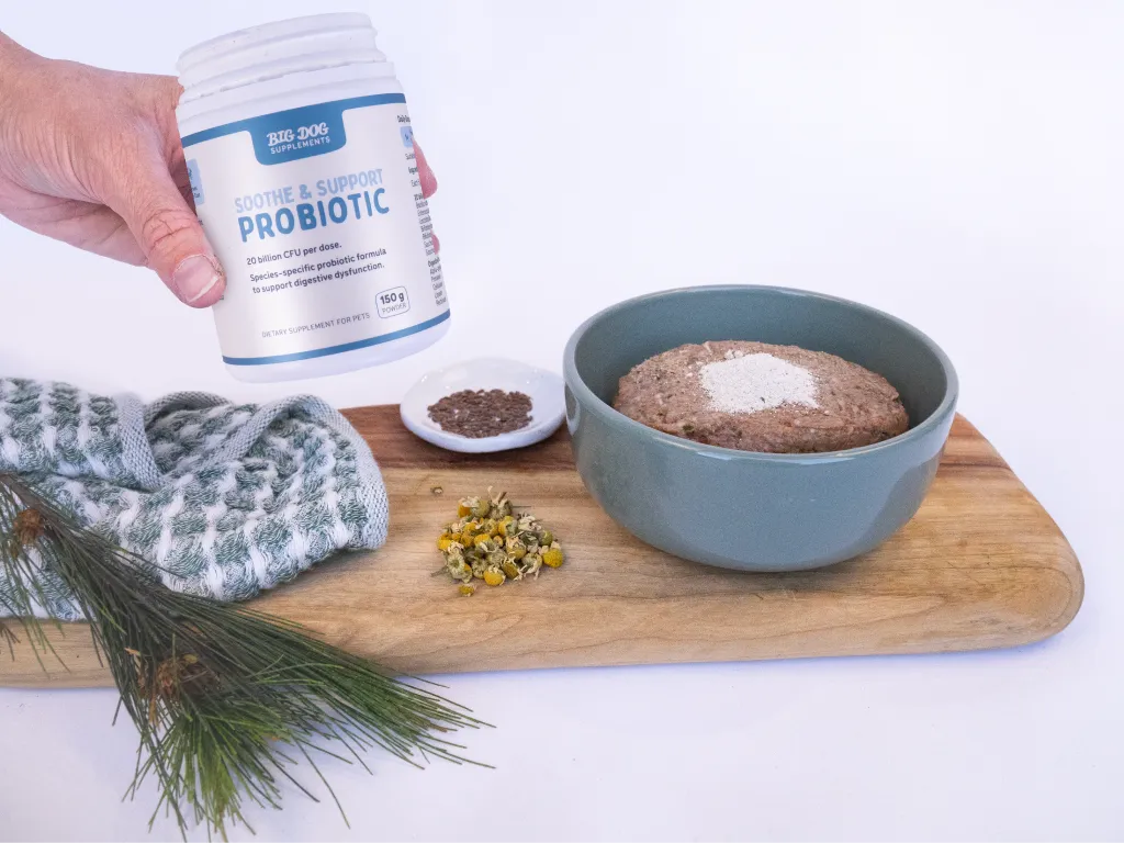 A hand holds a jar of Soothe and Support probiotic next to a bowl of dog food with Soothe and Support probiotic sprinkled on top.