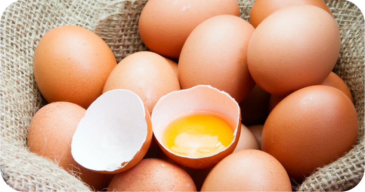 Photograph of a bunch of eggs in a hessian bag. One egg is cracked.