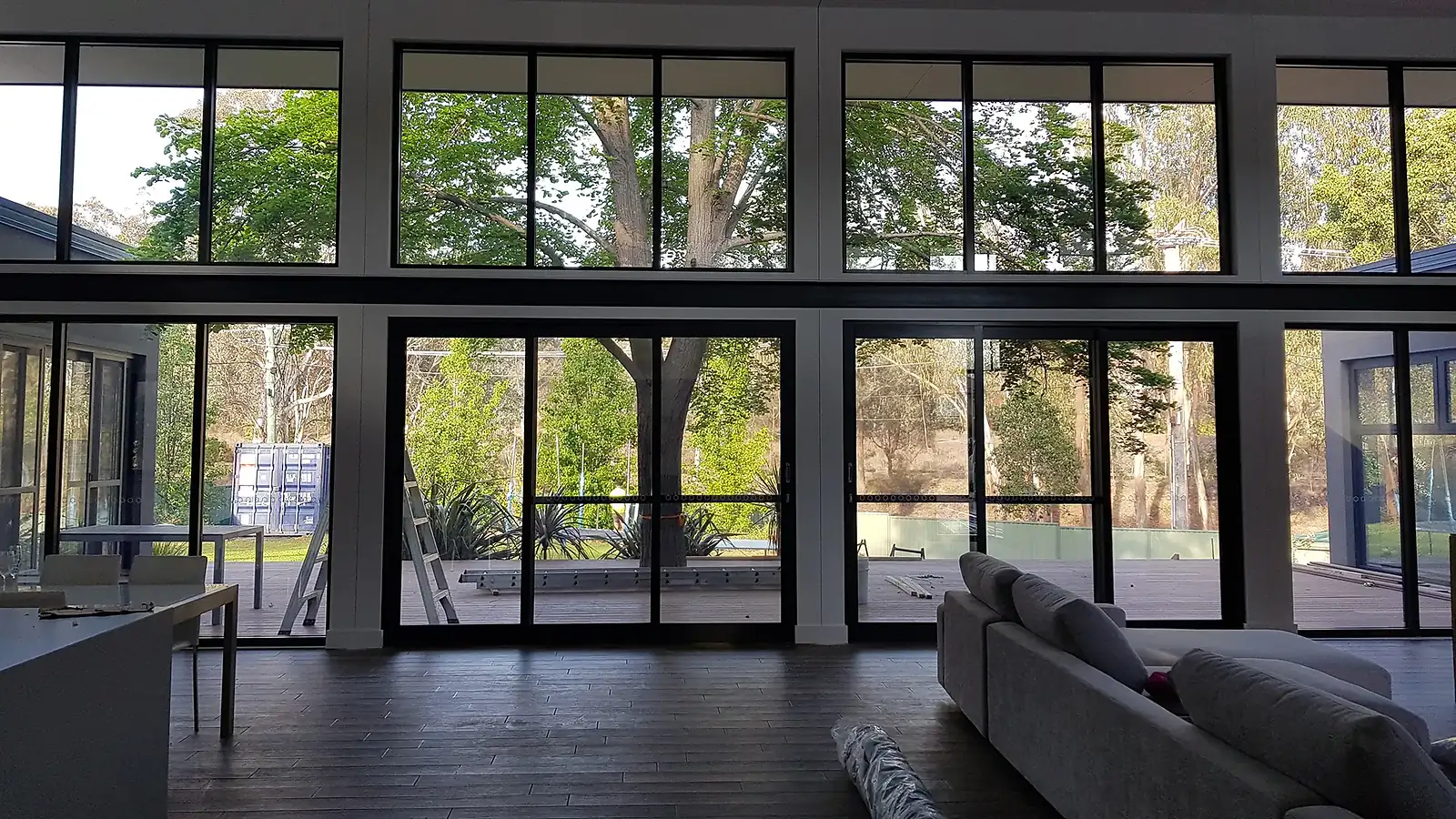 Living room with large floor-to-ceiling windows showing trees and a deck outside.