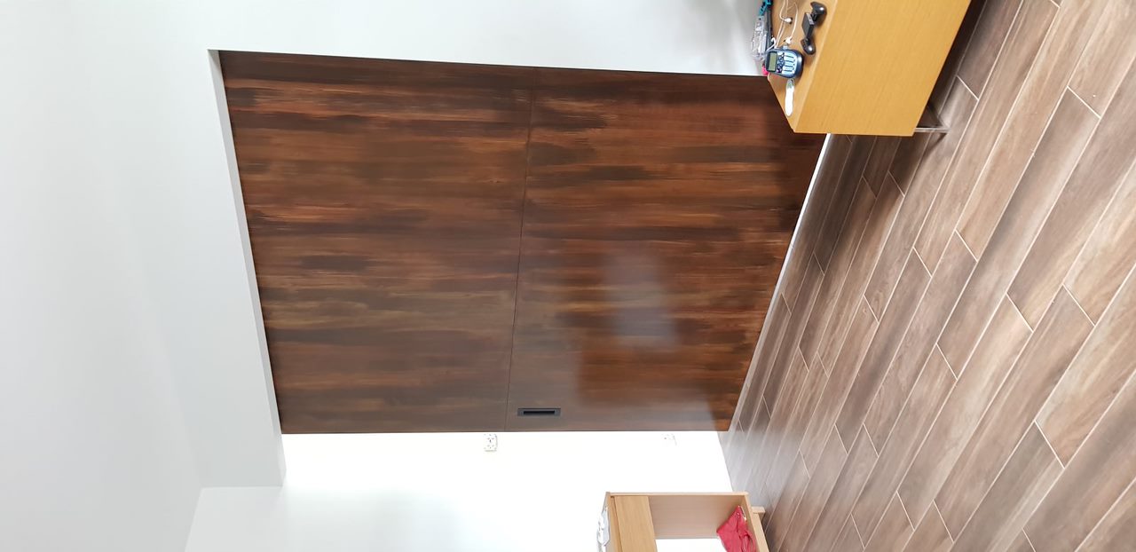 Room corner with large dark wood sliding door, wooden floor, and light wood furniture on each side.