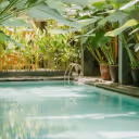 Indoor swimming pool surrounded by tropical plants and large green leaves.