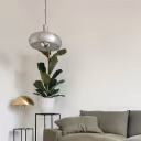 Modern living room with a gray sofa, green plant on a black side table, and two hanging pendant lamps.