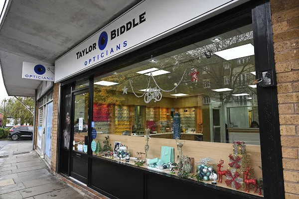 Taylor Biddle Opticians storefront with Christmas decorations in the window, including ornaments and red reindeer figures.