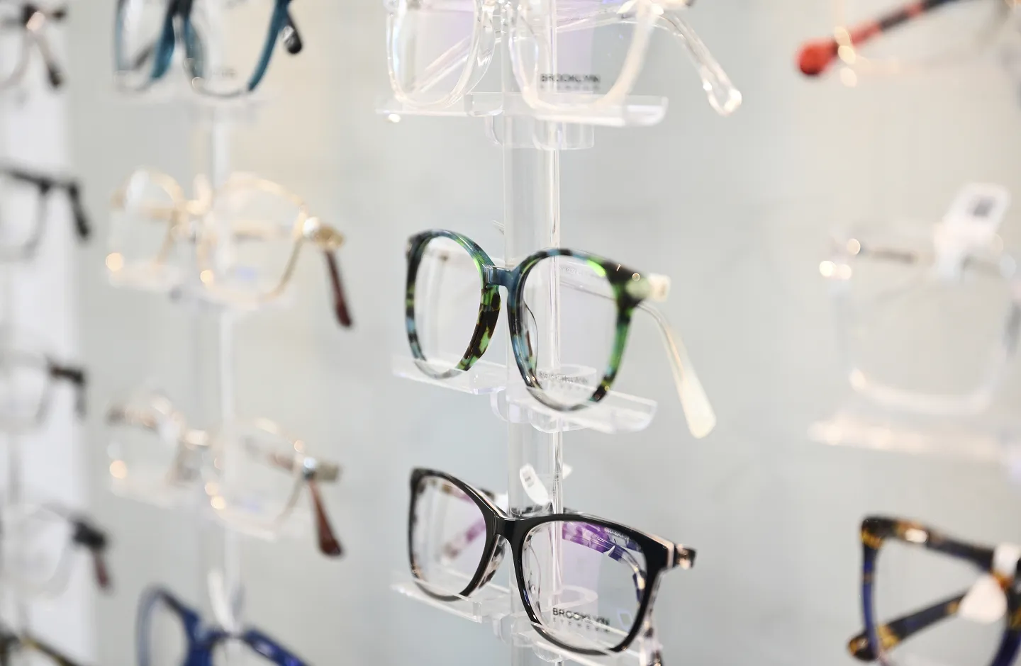 Display of various eyeglasses with different frame styles and colors in an optical store.