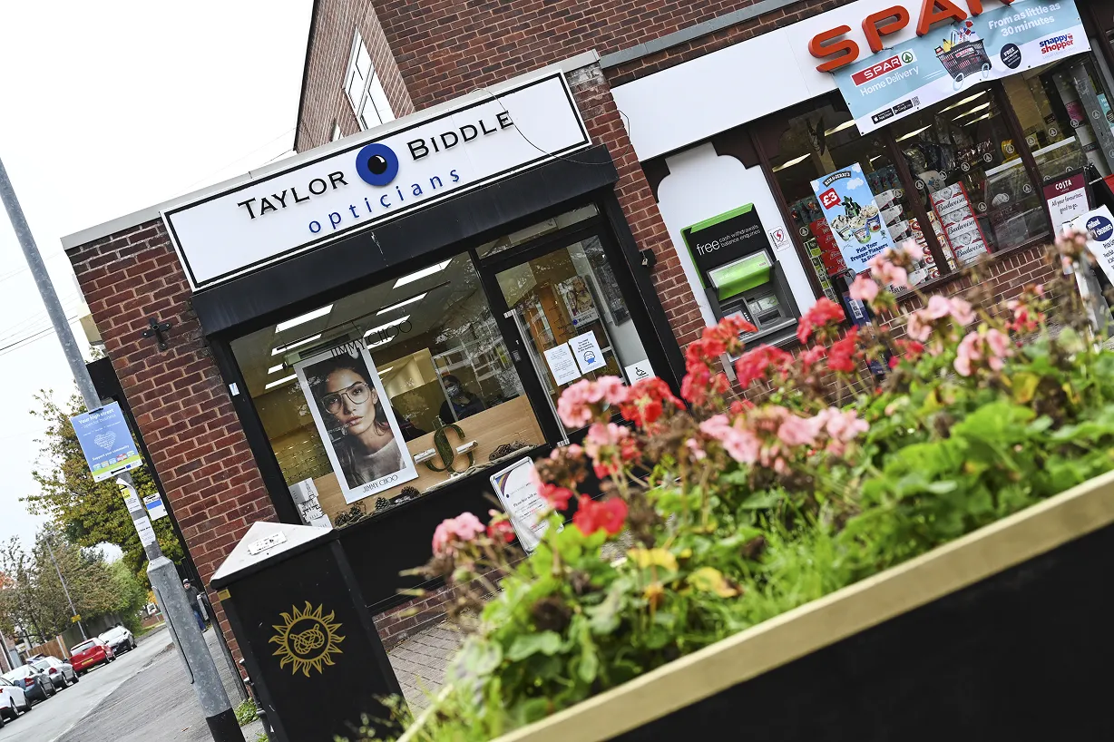 Street view of Taylor Biddle Opticians storefront with a Jimmy Choo eyewear poster and adjacent SPAR convenience store.