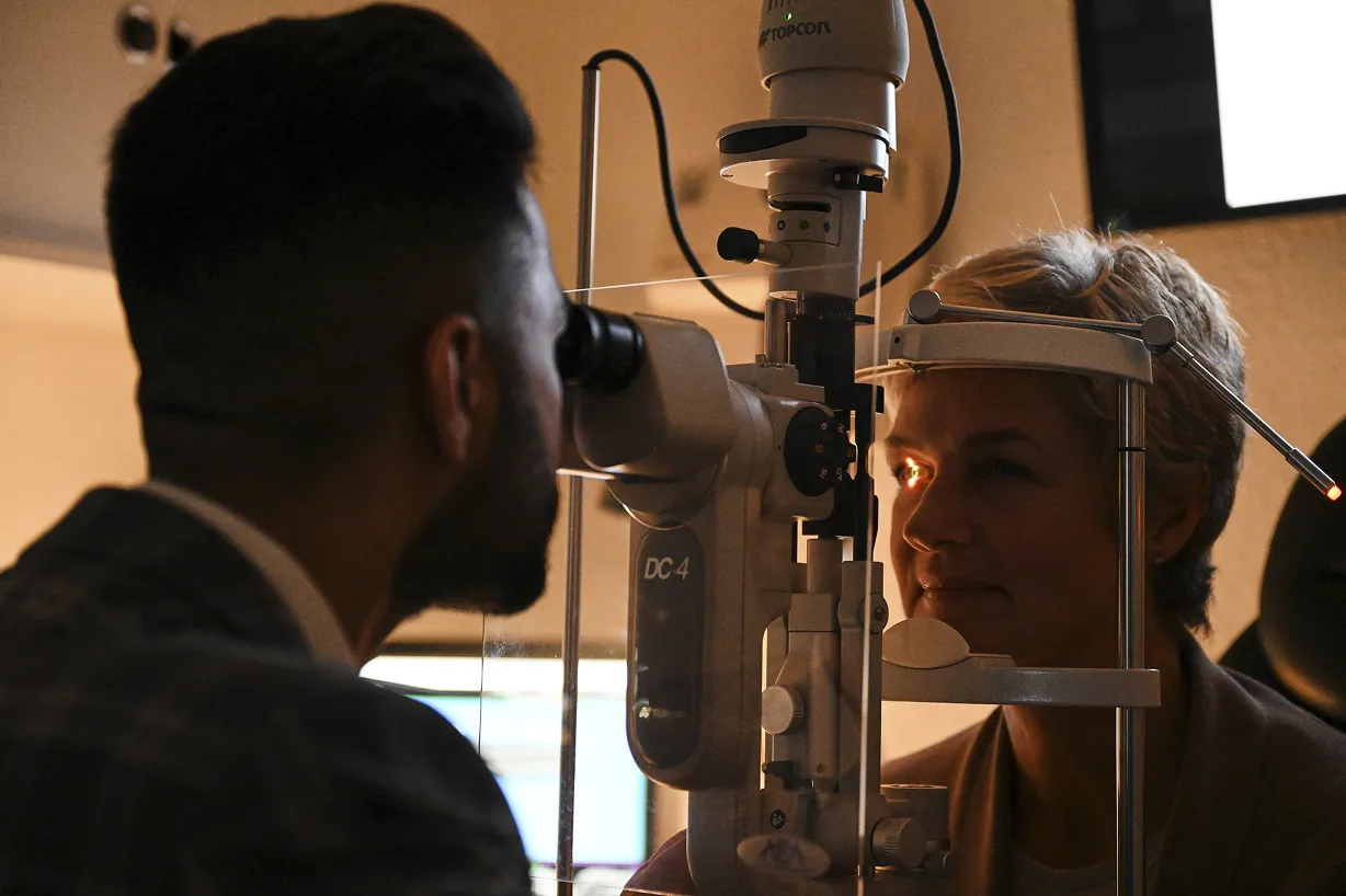 Eye doctor examining a patient's eye using a slit lamp in an ophthalmology clinic.