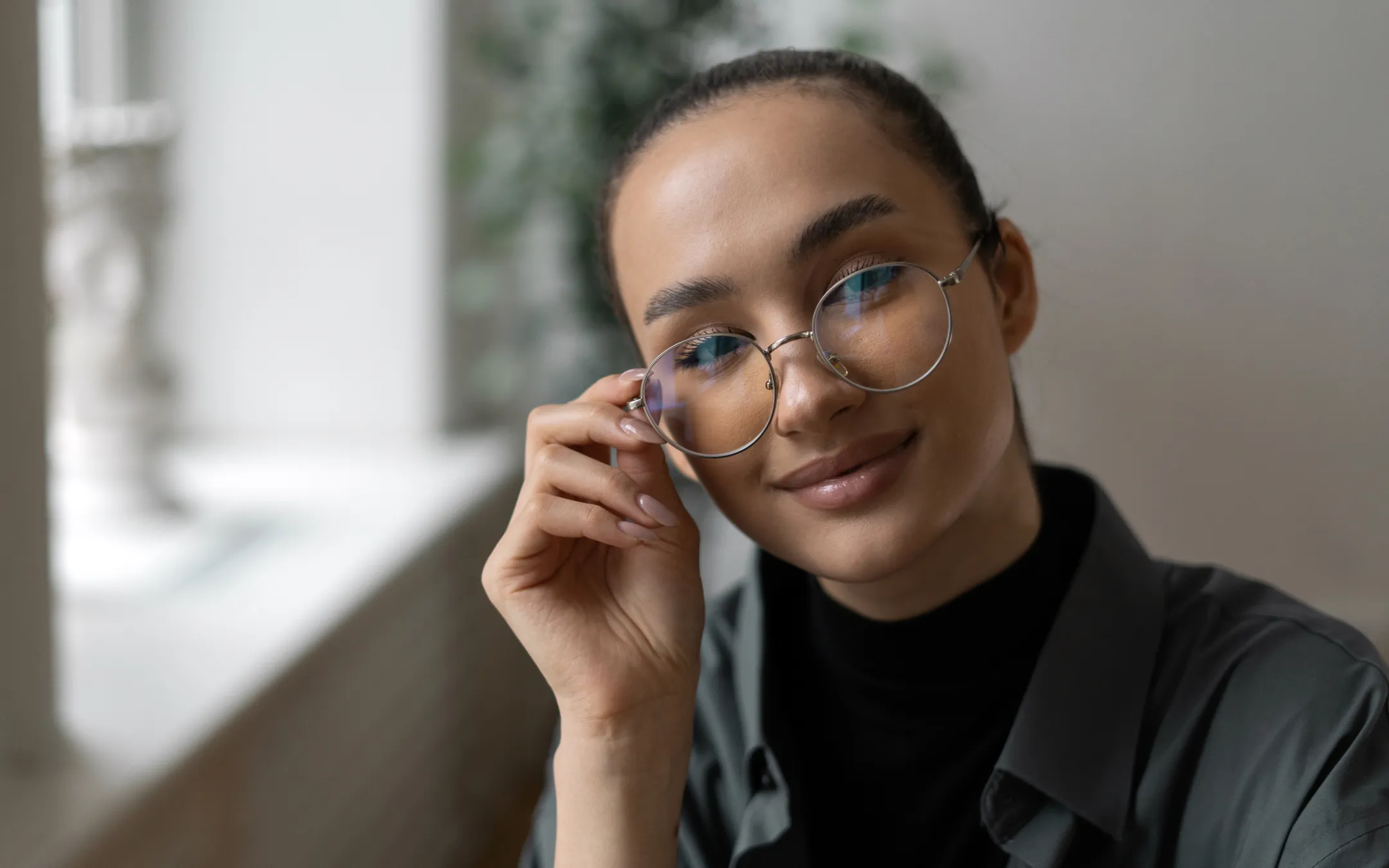 Smiling woman wearing fashionable round eyeglasses available at Wheeldon opticians
