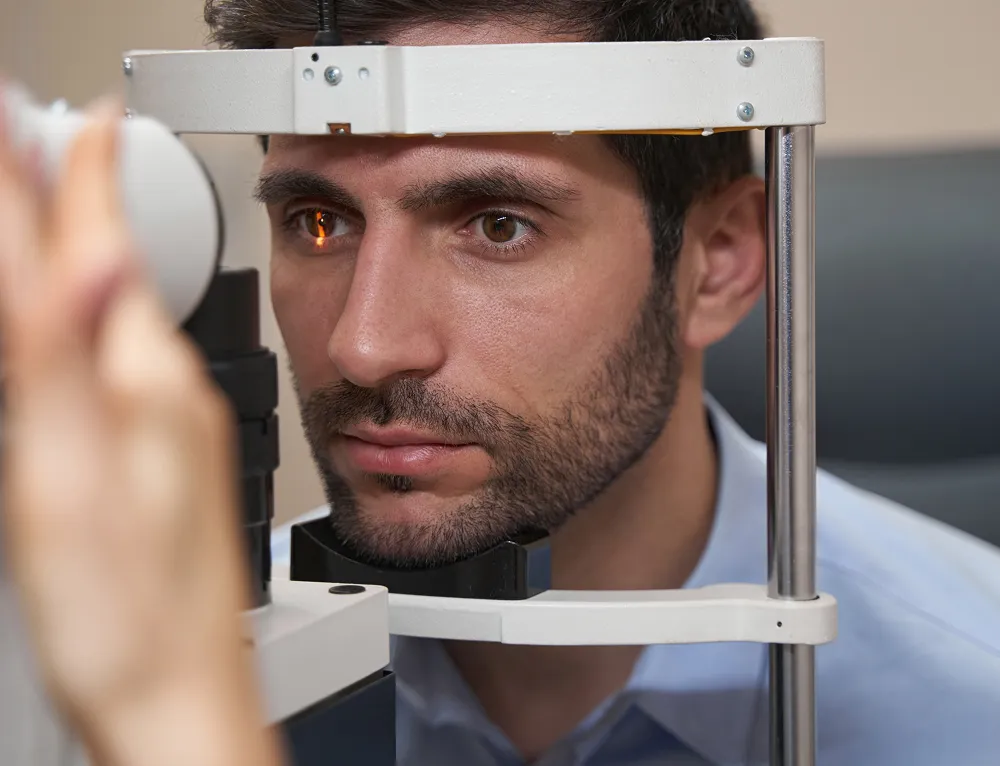 Man undergoing an eye examination with a slit lamp in an optometrist's office.