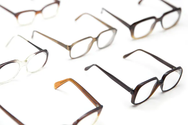 Various pairs of eyeglasses with different frame styles arranged on a white surface.