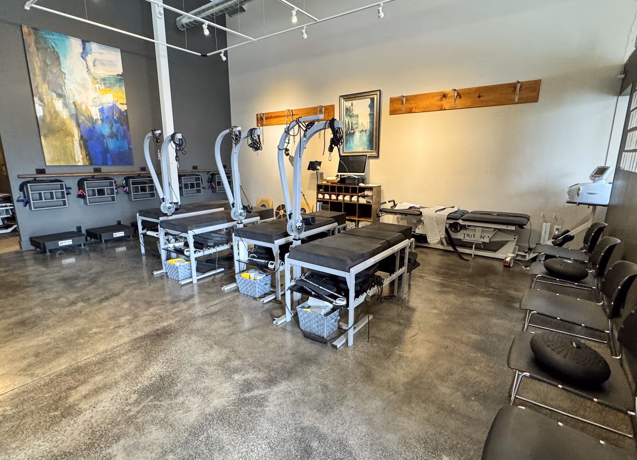 Modern chiropractic clinic treatment room with spinal decompression tables, rehabilitation equipment, and patient seating used for vertigo, neck pain, and balance disorder care.