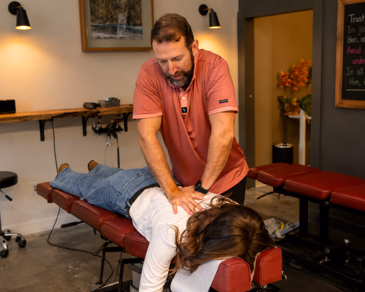 Dr. Ben Ozanne applying a chiropractic adjustment to a patient's upper back during a treatment session.
