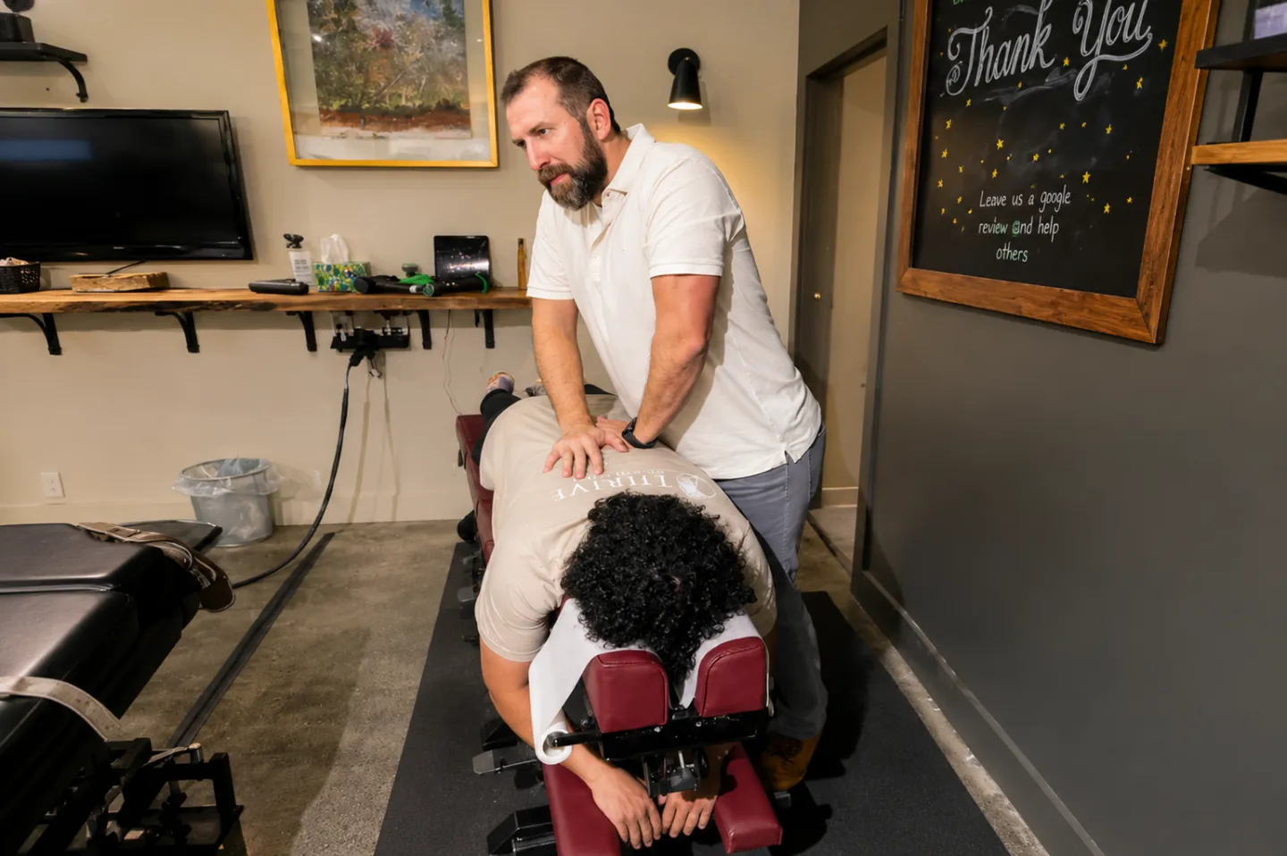 Dr Ben Ozanne performing a hands-on back adjustment on a patient lying face down at Thrive Wellness Center.