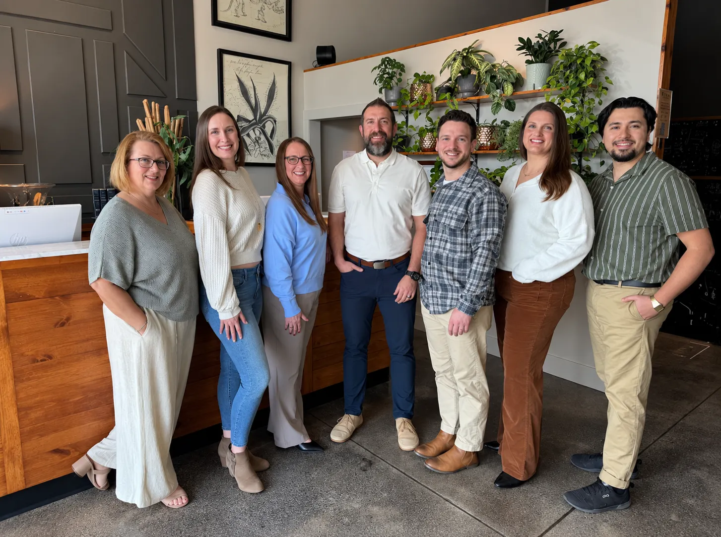 Seven members of the Thrive Wellness Center team standing together and smiling in the clinic reception area.