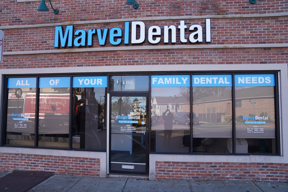 Facade of Marvel Dental clinic with brick walls, large windows displaying 'All of Your Family Dental Needs' and the clinic's name above the entrance.