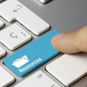 Close-up of a finger pressing a blue keyboard key labeled 'Resources' with a folder icon.