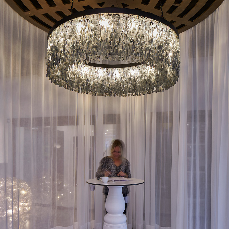 A white halo chandelier installed in a Swiss lighting showroom