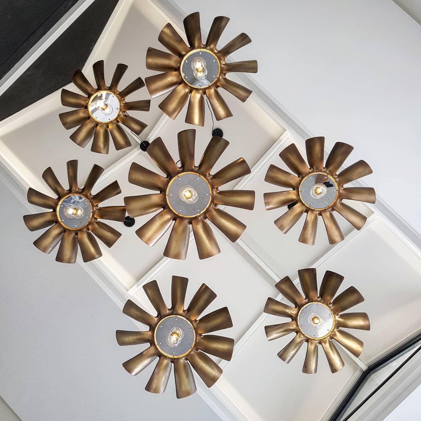 Many brass blow masculine pendants in a double volume space