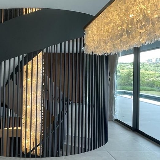 Sea glass lighting sculpture by Stephen Pikus Design cascading through a three-storey staircase