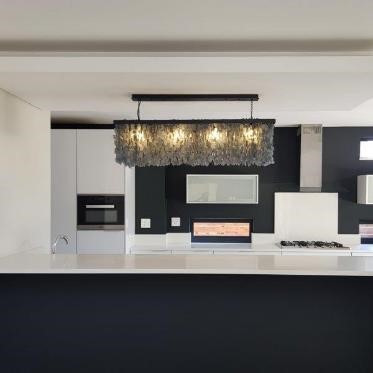 A charcoal linear chandelier in a monochromatic kitchen