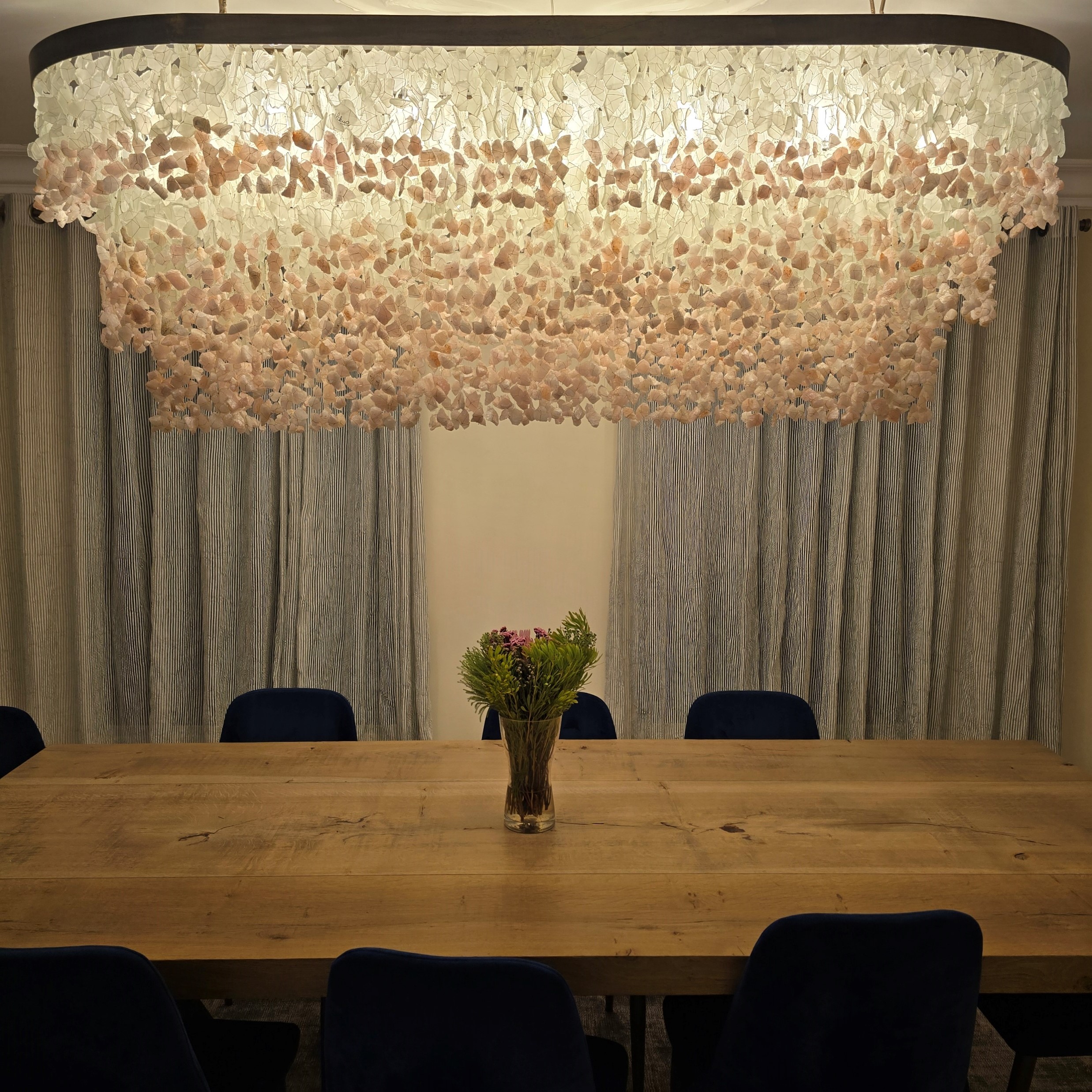 A customized white and rose quartz chandelier over a Pierre Cronje table