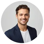 Smiling young man with short brown hair wearing a navy blazer and white shirt against a light gray background.