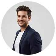 Smiling young man with dark hair wearing a navy blazer and white shirt against a light gray background.