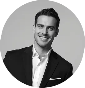 Smiling man in a black suit jacket and white shirt against a plain background.