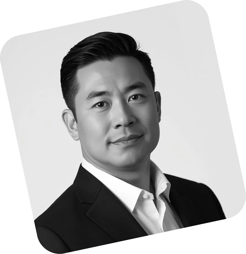 Black and white portrait of a man wearing a dark suit jacket and white shirt, looking into the camera with a slight smile.