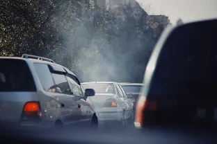 Traffic jam with visible exhaust smoke from cars on a city street.