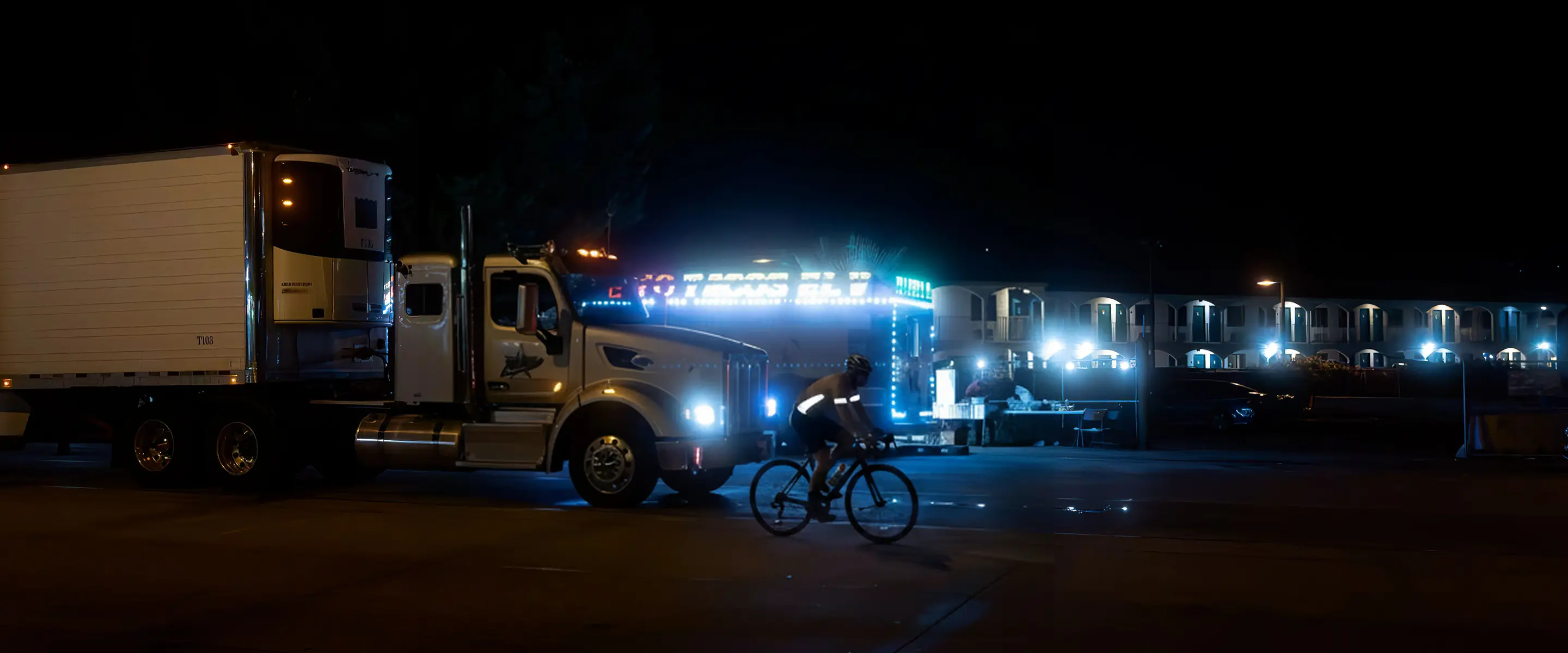 Night scene with a semi-truck and a cyclist in front triggering a blind-spot alert.