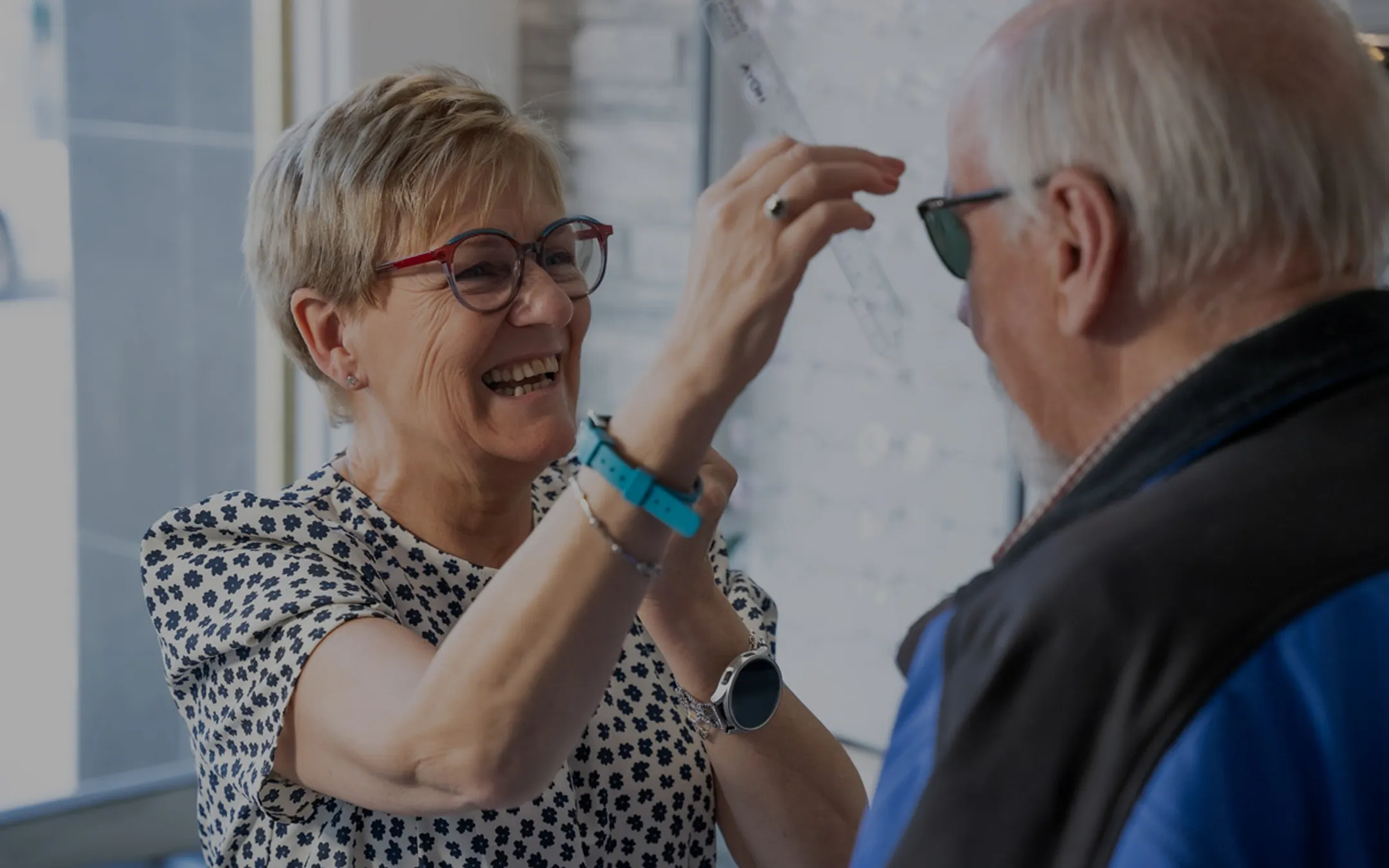 Optician fitting glasses on an elderly male patient during a tailored eye care consultation