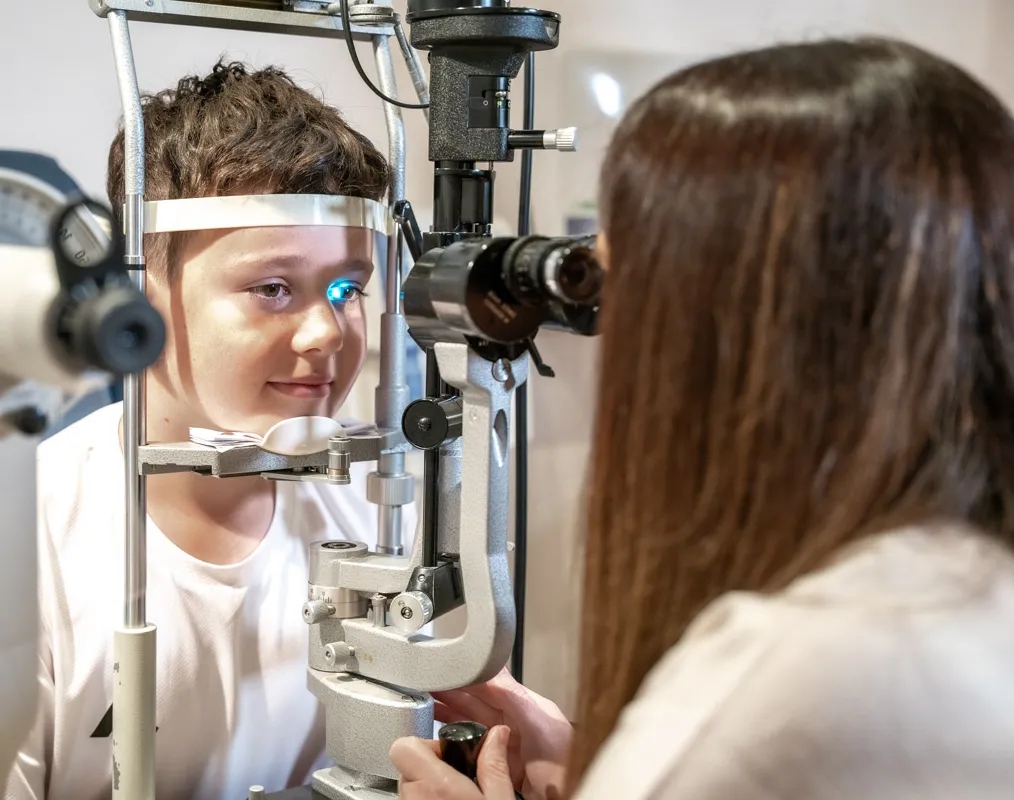 Young child undergoing slit lamp eye examination during children's eye test at independent opticians