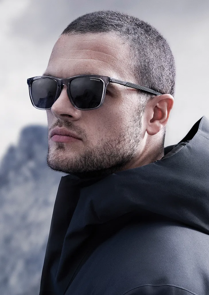 Man wearing Defender grey square polarised sunglasses outdoors against mountain backdrop