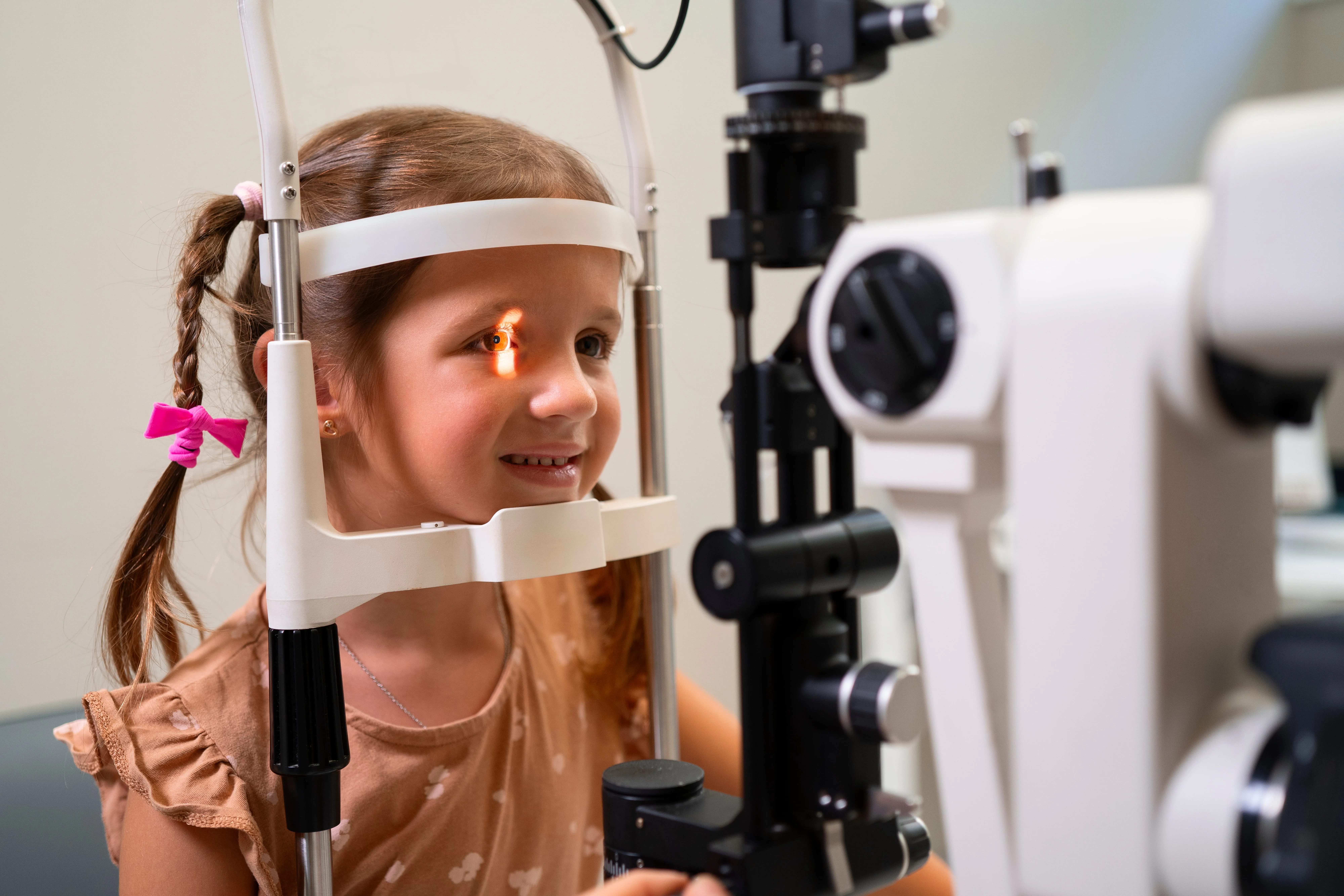 Young girl undergoing eye examination with optical equipment and light test