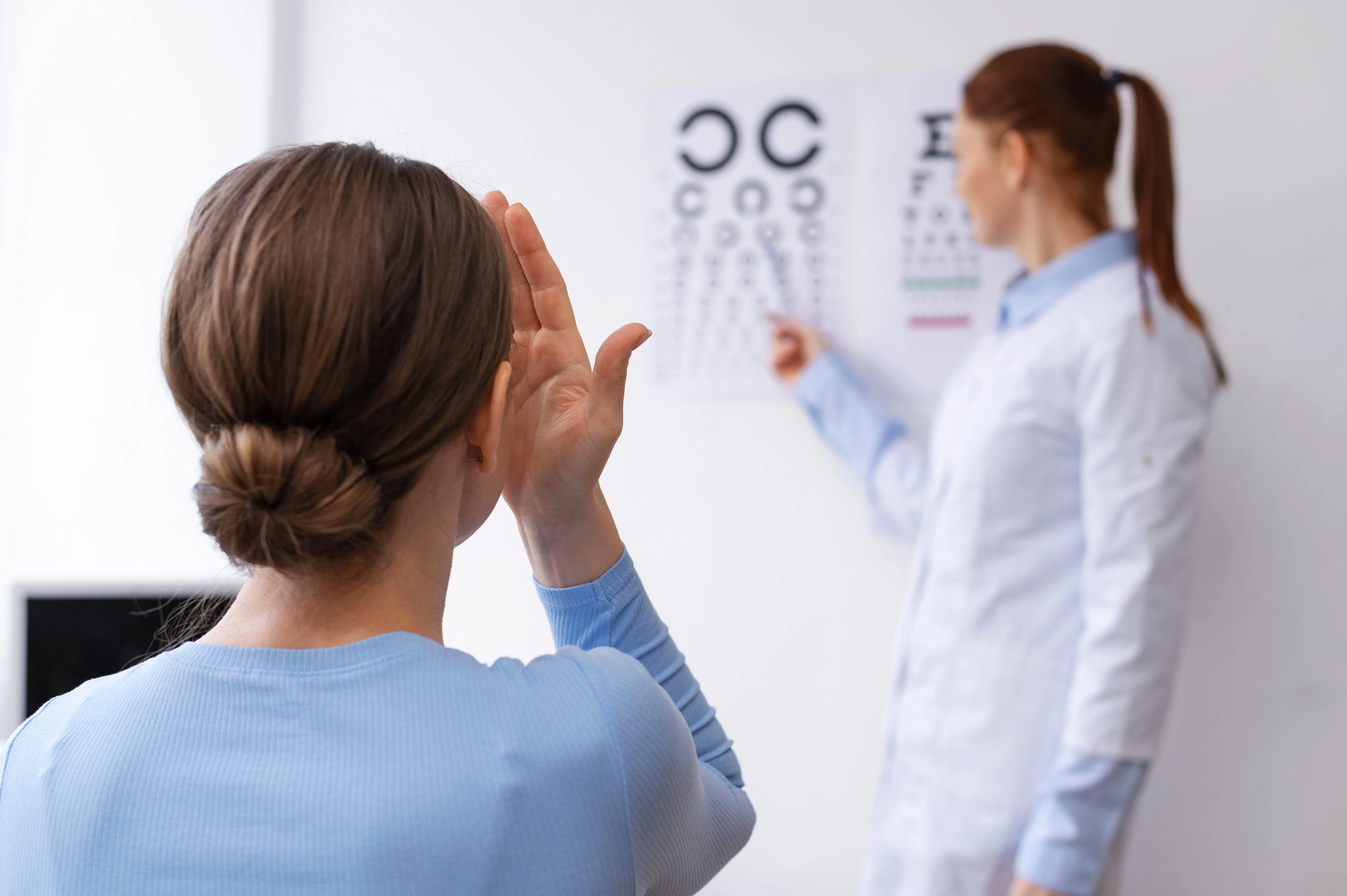 Eye doctor tests patient's vision using eye chart during medical examination