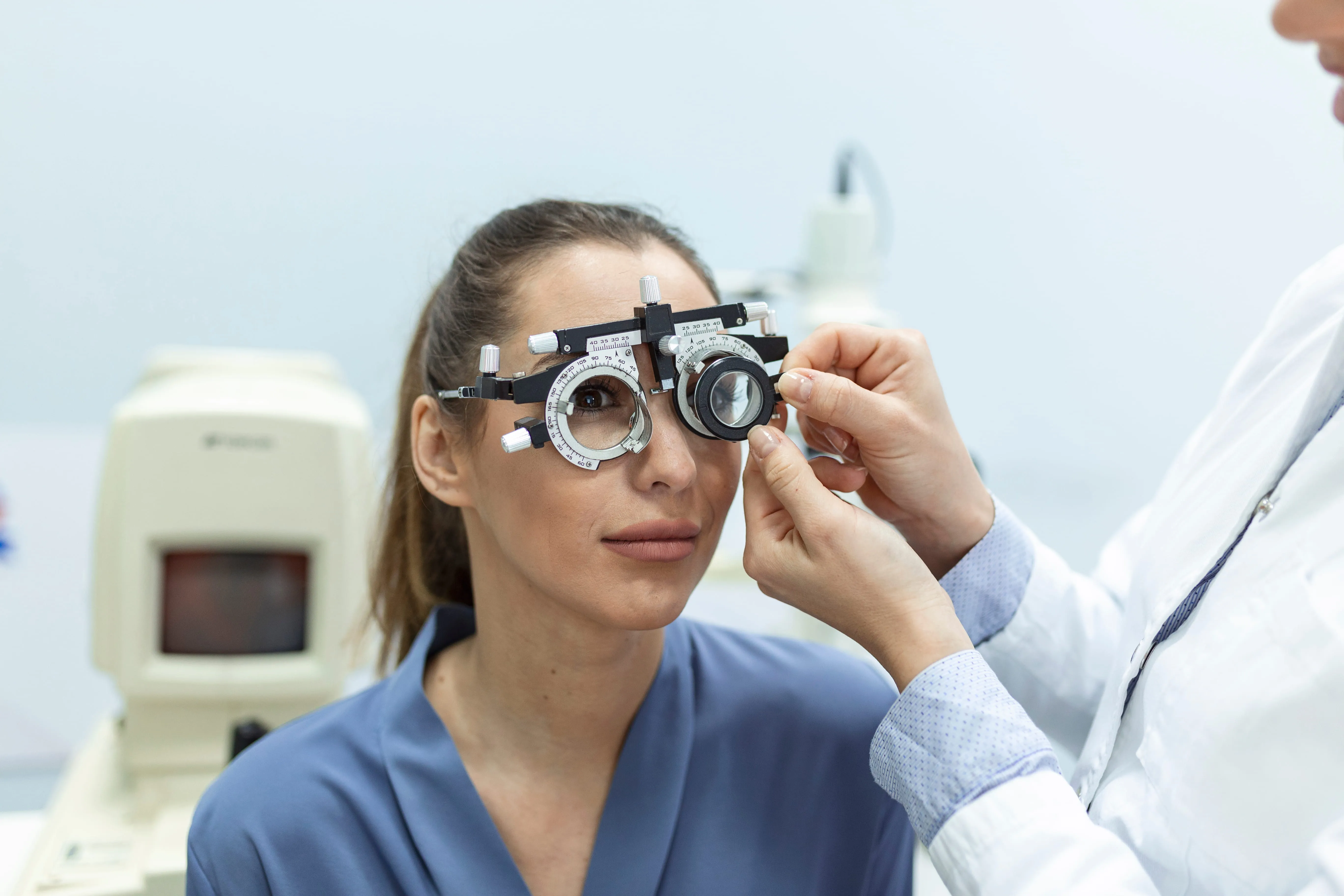 Optometrist adjusting phoropter for patient eye examination and vision testing