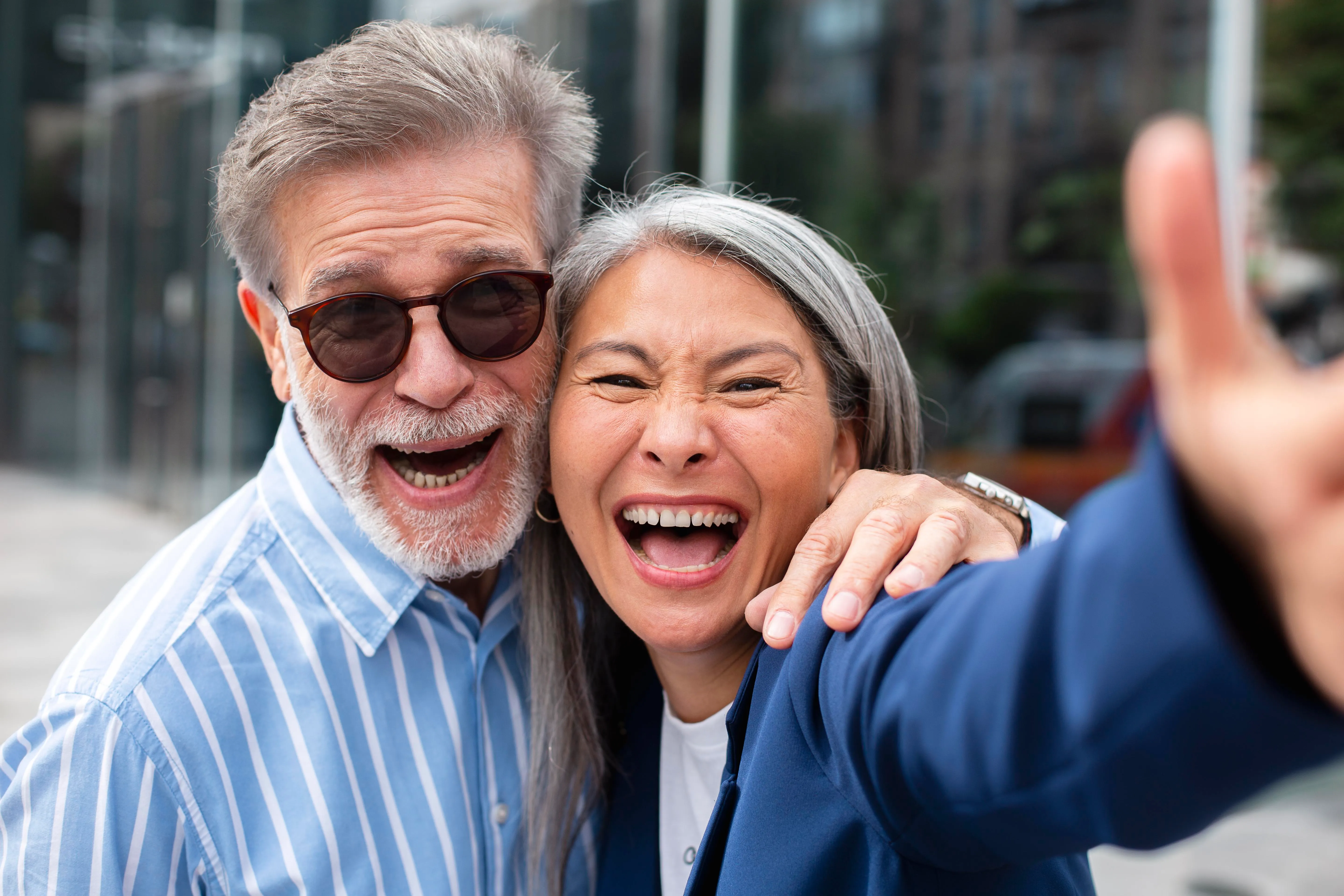 Happy senior couple laughing outdoors together taking a selfie