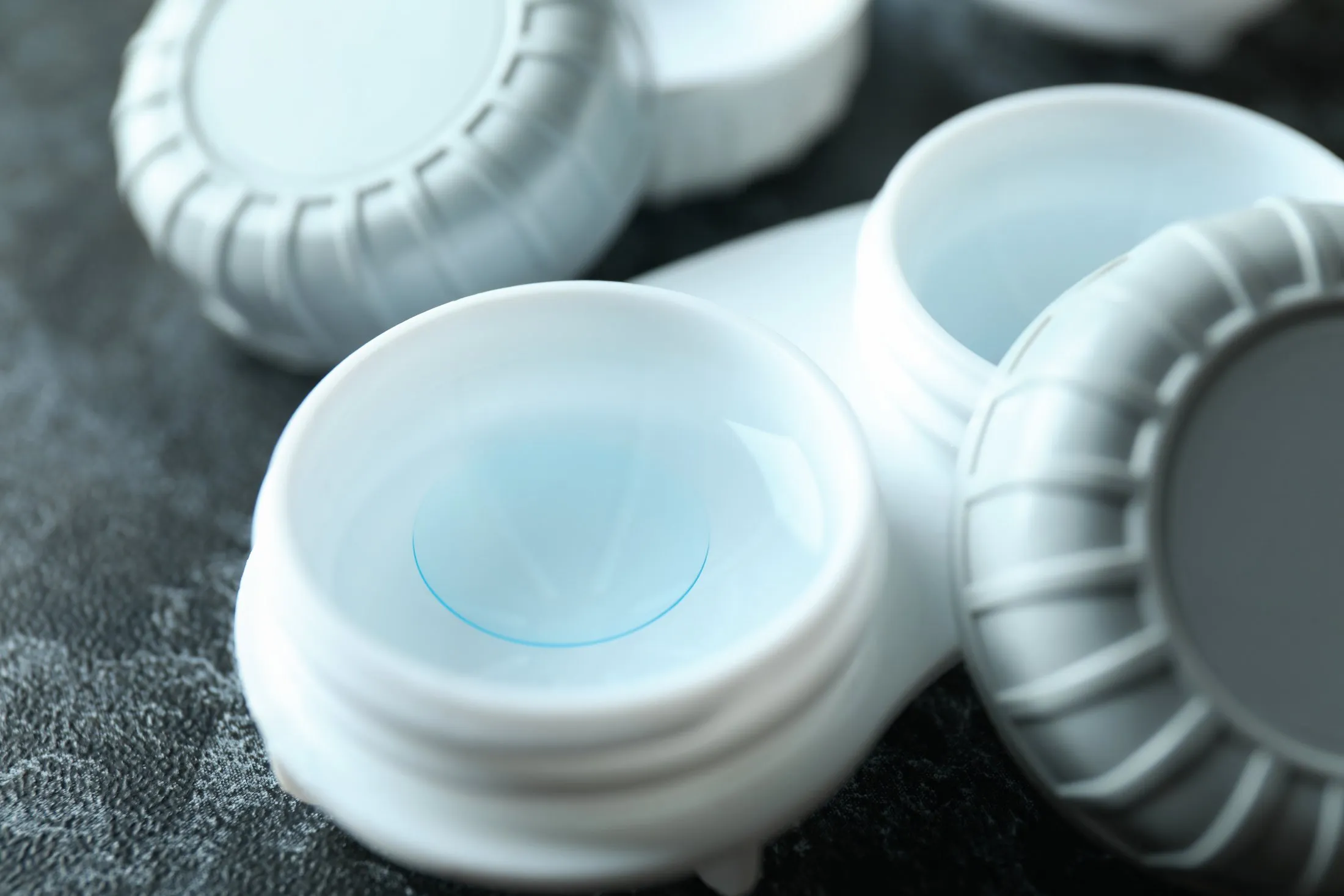 Close-up of a contact lens soaking in solution inside a white plastic lens case.