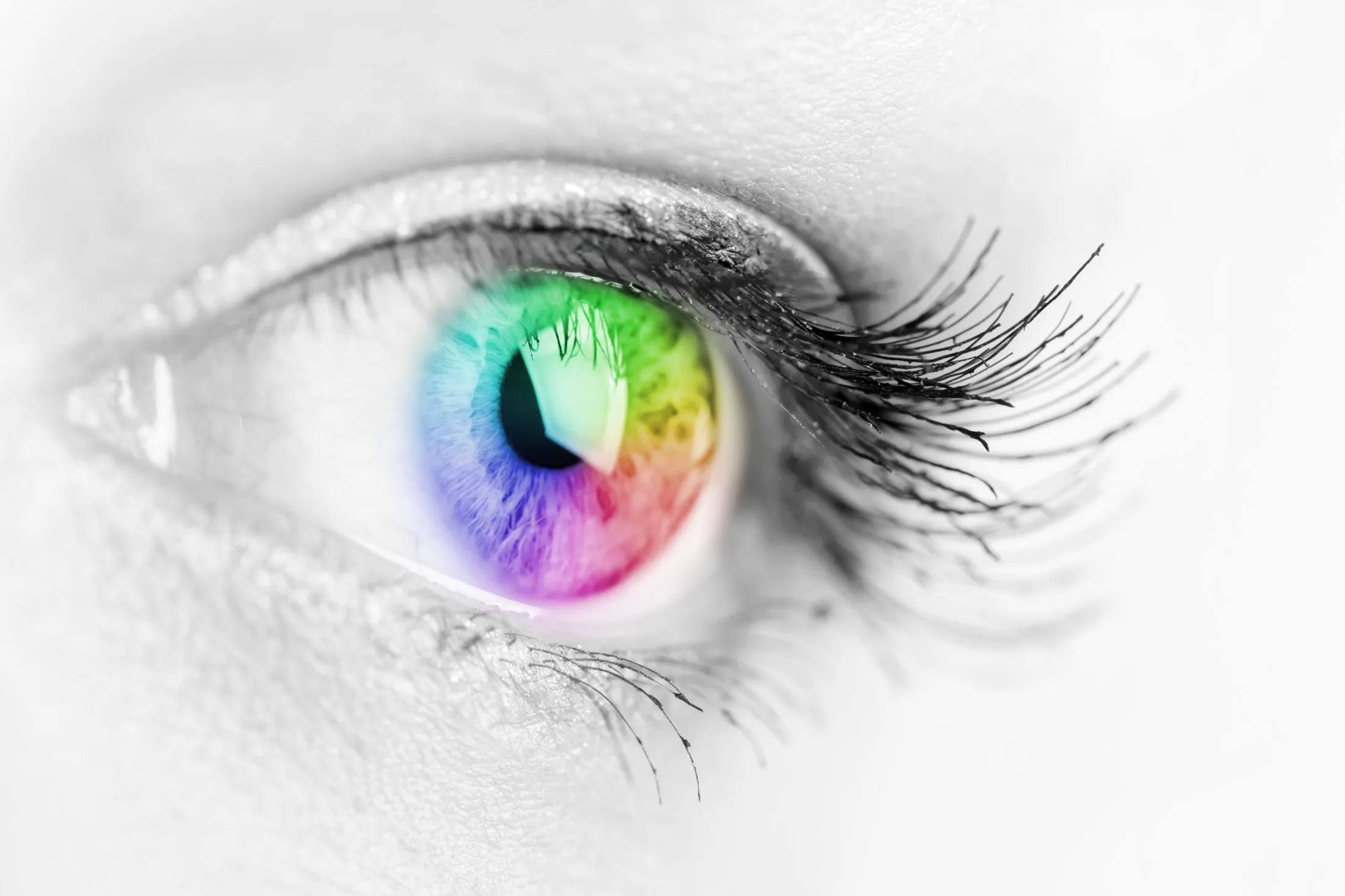 Close-up of an eye with a colorful rainbow iris and long eyelashes in black and white skin.