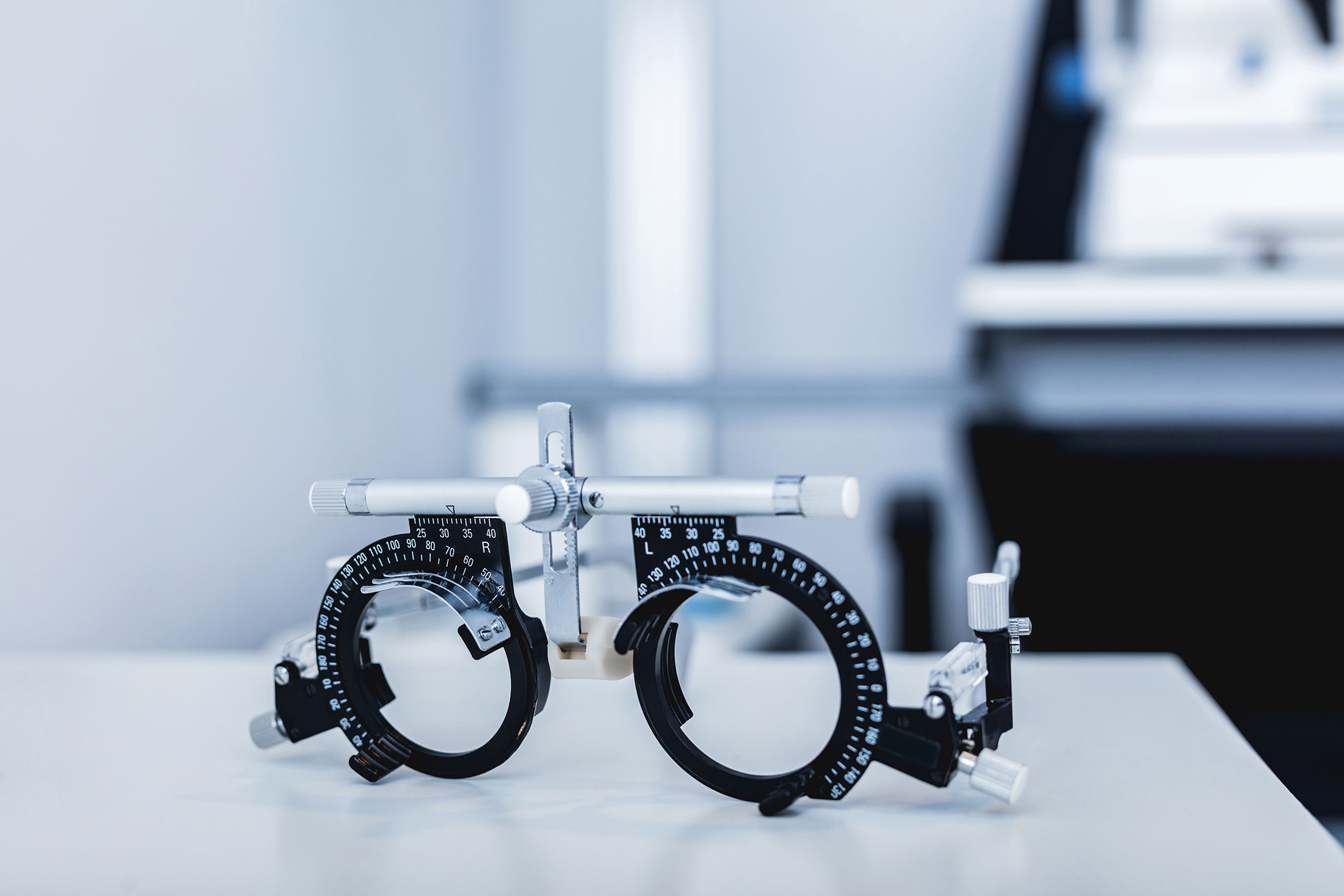 Close-up of an optometry trial frame used for eye exams, placed on a white surface.