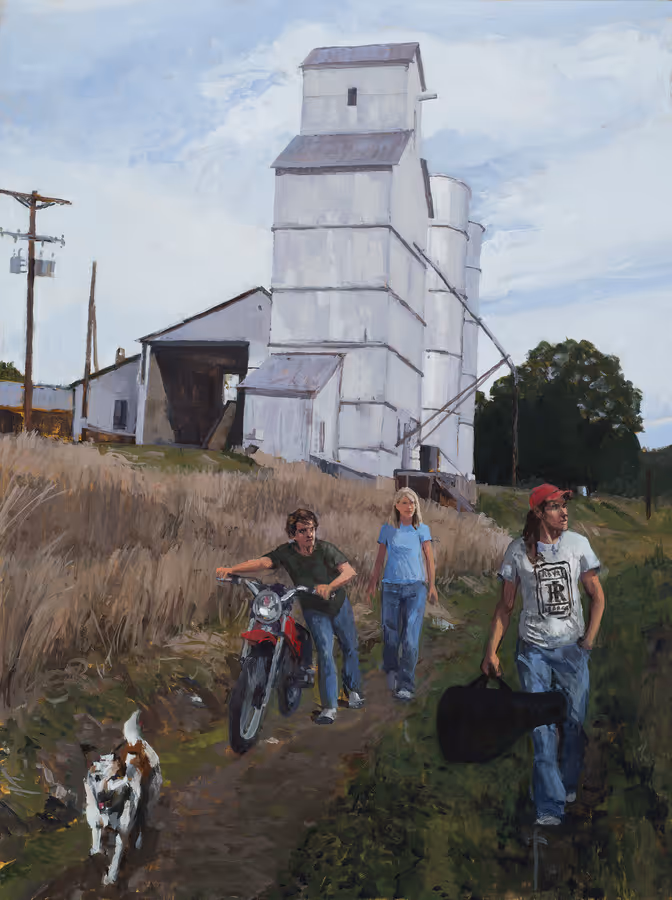 Three people and a dog on a dirt path near tall white industrial silos on a partly cloudy day.