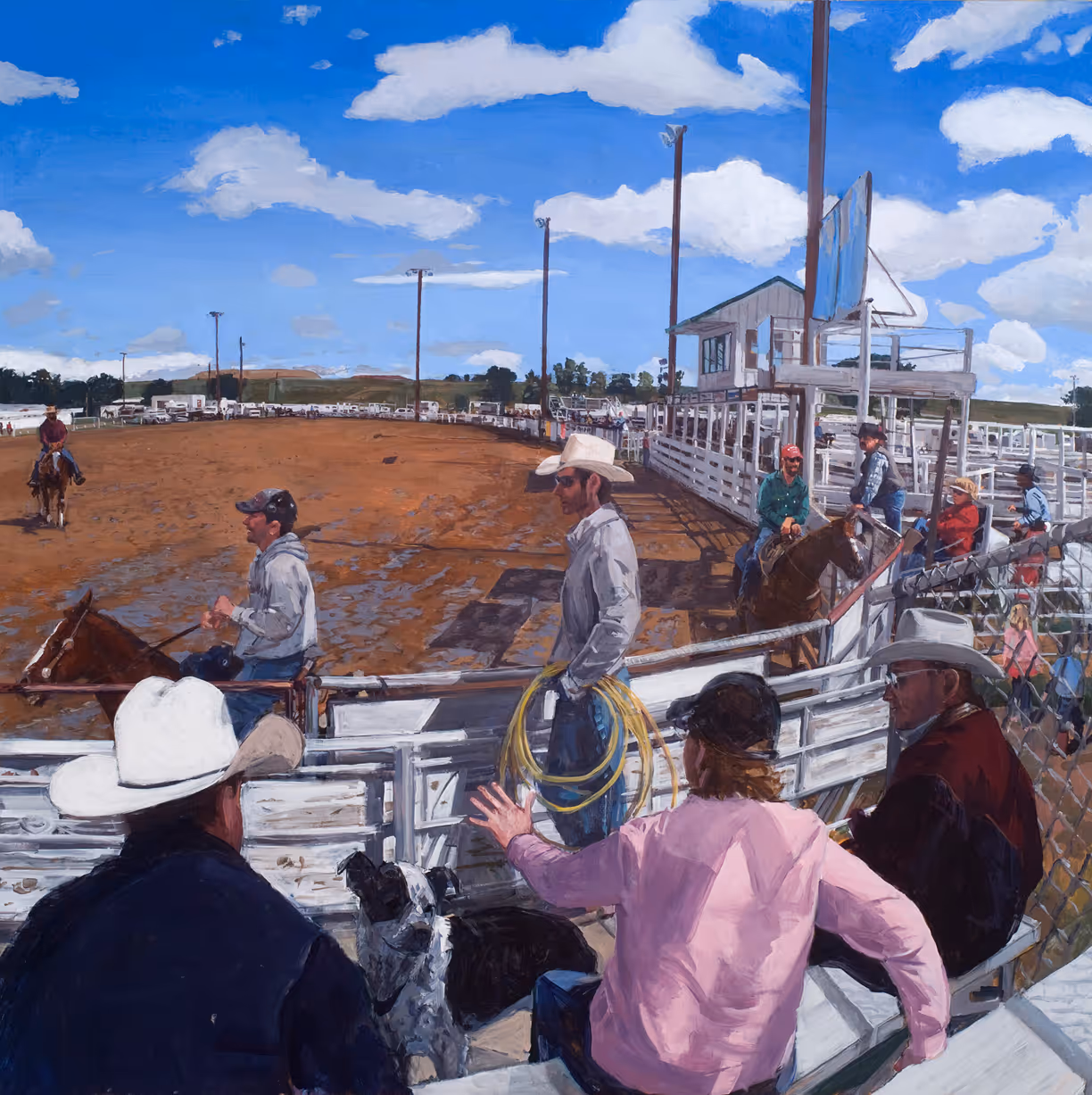 Cowboys and spectators gather at a rodeo arena under a bright blue sky with scattered clouds.