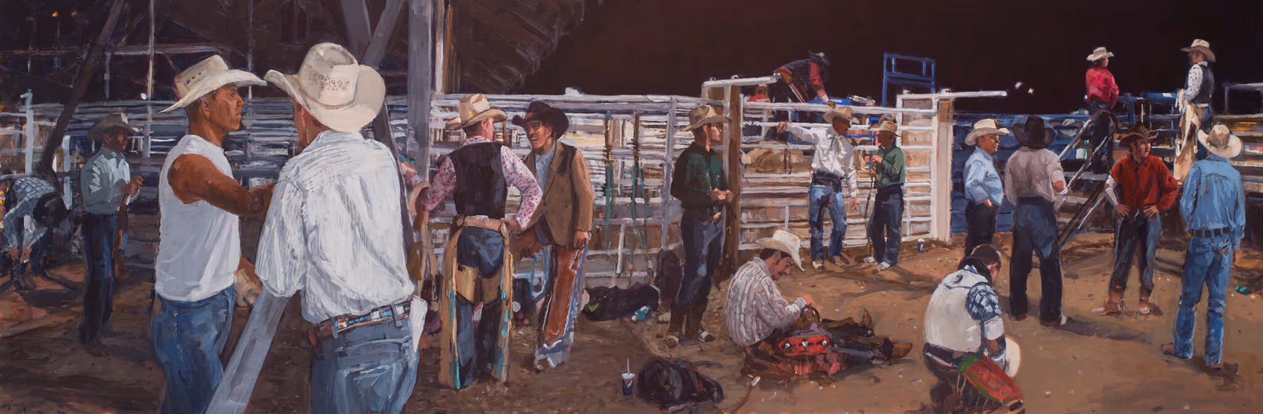 Cowboys in hats and western wear gather in a rodeo arena preparing for an event at night.