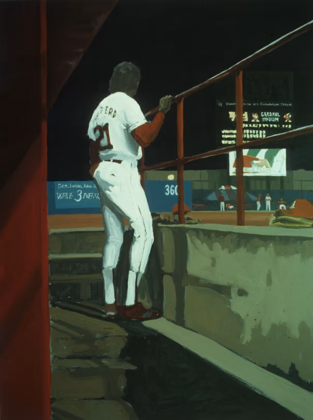 Baseball player in white uniform with number 21 leans on railing, watching a night game at stadium.