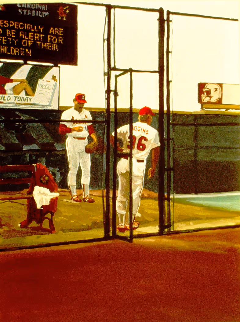 Two baseball players in red and white uniforms practicing on a bullpen mound behind a protective fence.