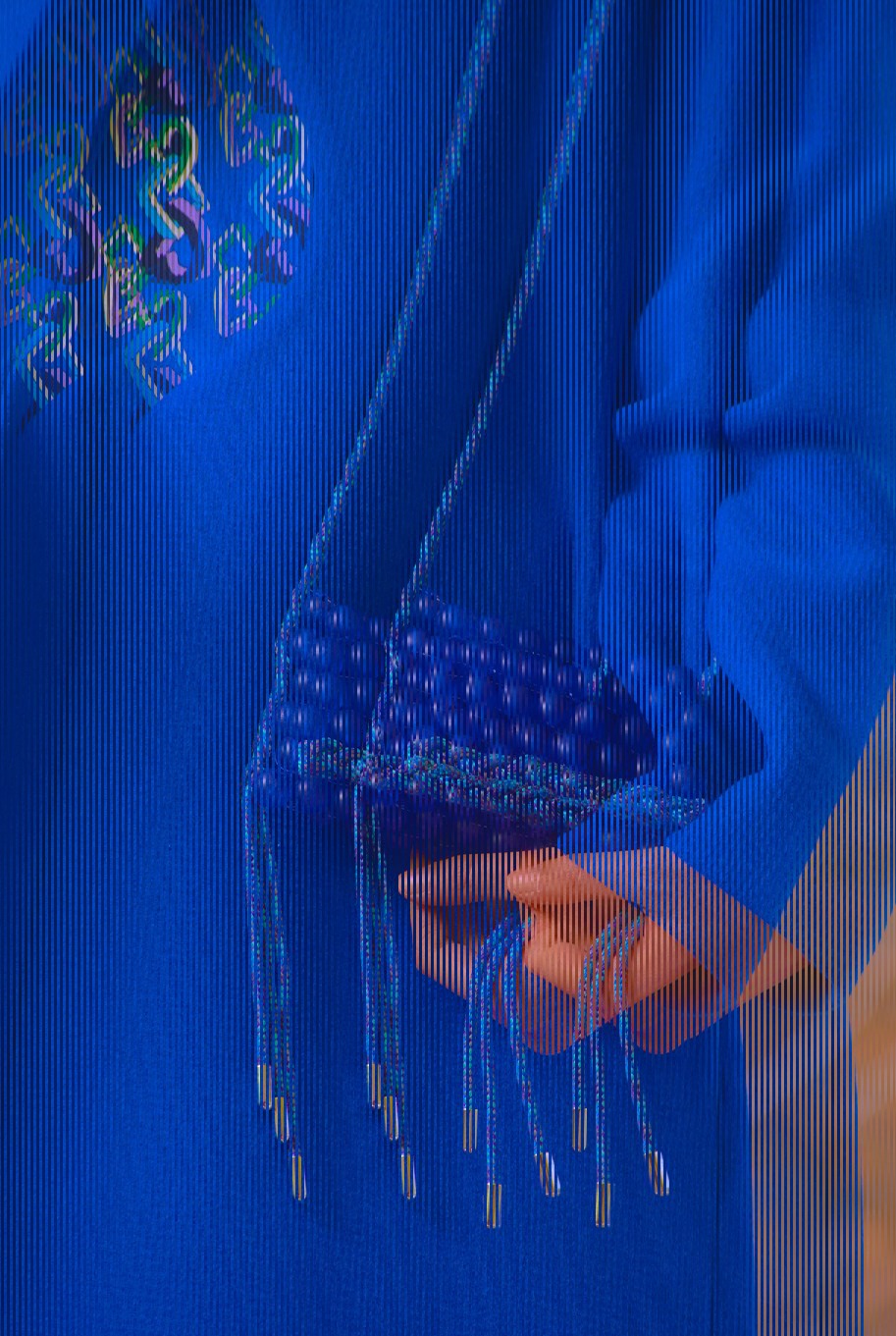 Model in white trousers and cropped top against draped blue fabric
