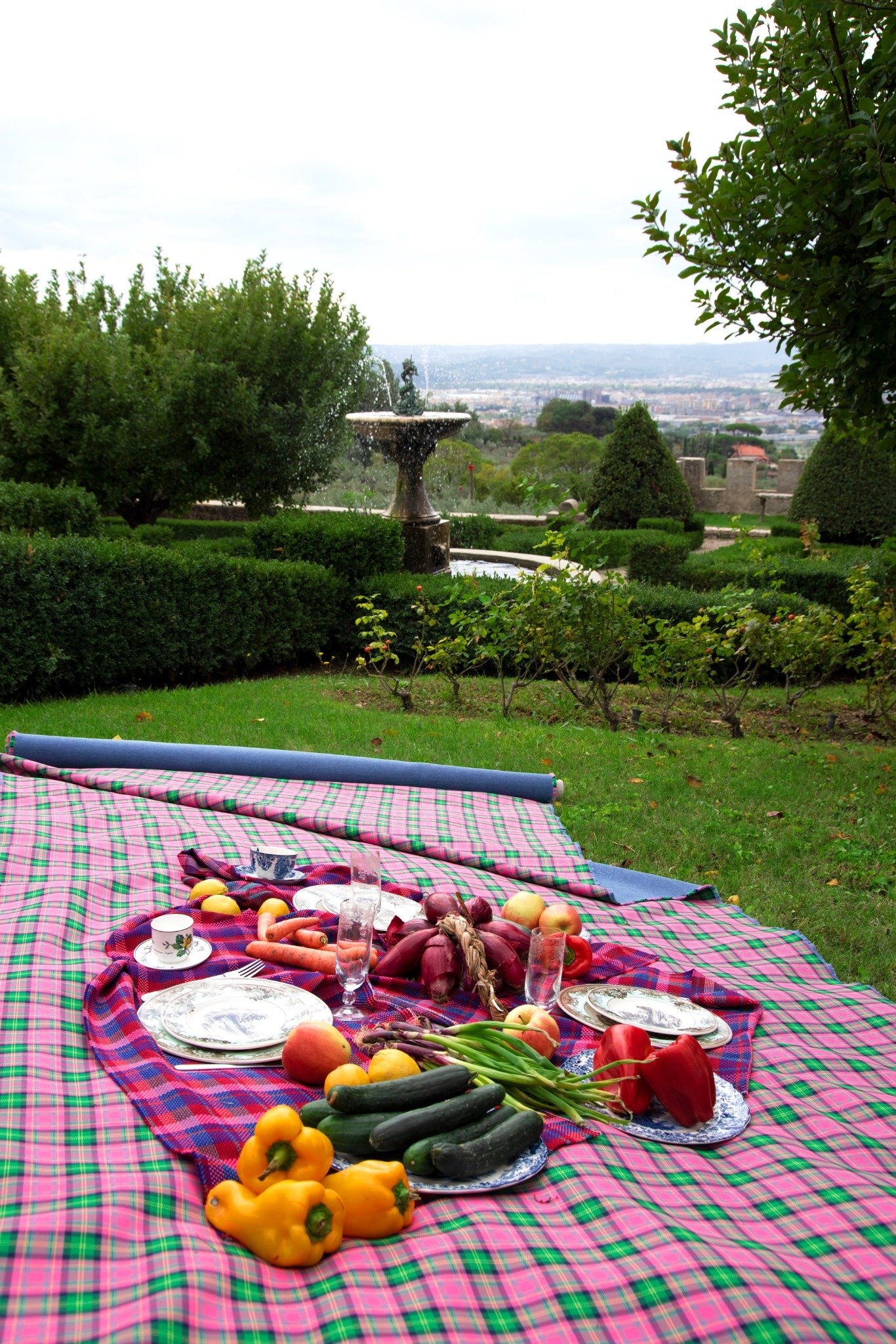 Picnic laid on a checked blanket overlooking a garden and valley