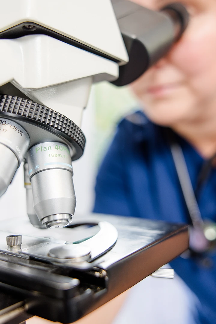 Laborfotografie im medizinischen Bereich – Mitarbeiterin bei Analyse am Mikroskop