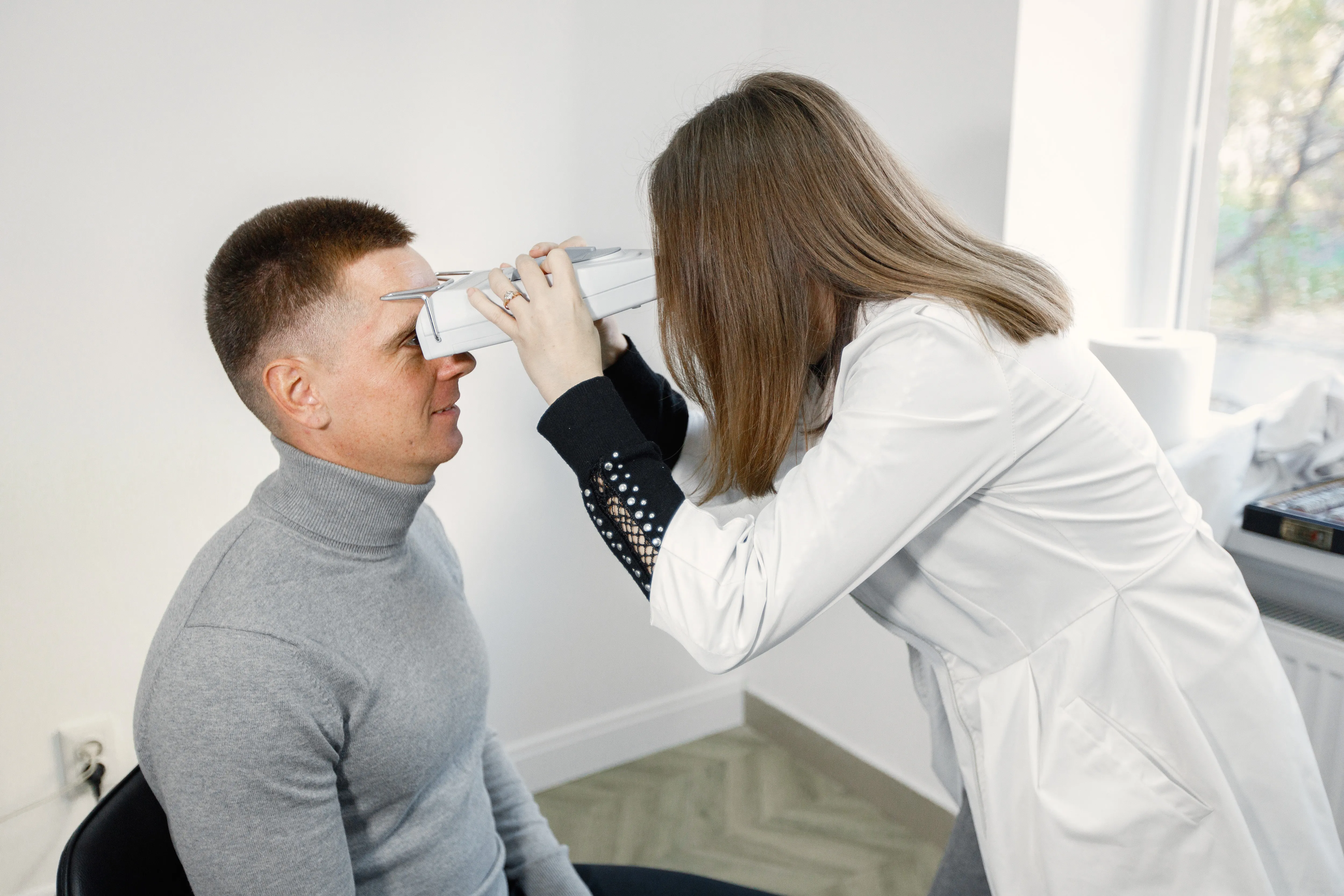 Healthcare professional using phoropter to examine patient's eyes during vision test